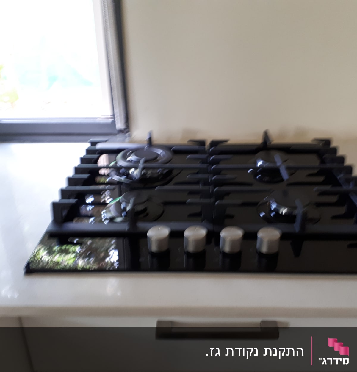 כיריים גז שחורות עם ארבעה מבערים וכפתורים כסופים